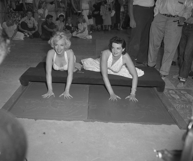 Marilyn Monroe and Jane Russell putting handprints in cement at Chinese 