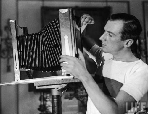 Photographer Cecil Beaton adjusting the lens on a primitive camera in his studio-- Circa 1929.