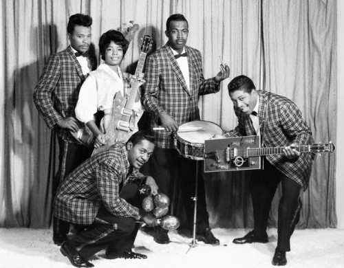 Norma-Jean "The Duchess" Wofford in white blouse, Jerome Green squatting in front with maraca, and Bo Diddley with his signature Gretsch guitar --late 1950s.