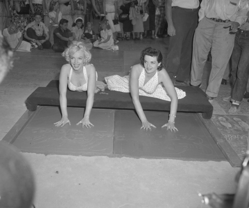 Marilyn Monroe and Jane Russell putting handprints in cement at Chinese Theater in Los Angeles, CA  --circa 1953.