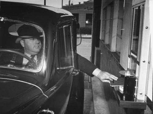 Motorist in his car making a transaction at the drive up window of a bank --ca. 1938.