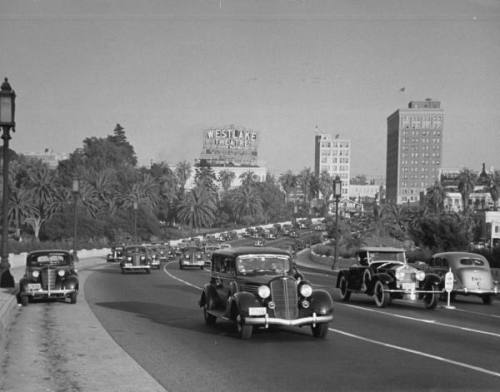 Auto traffic on Wilshire Boulevard during rush hour with sign for the WESTLAKE THEATRE looming in the background --ca. 1938.